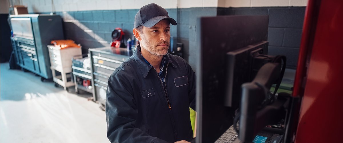 Technician in a service bay looking up parts on a computer