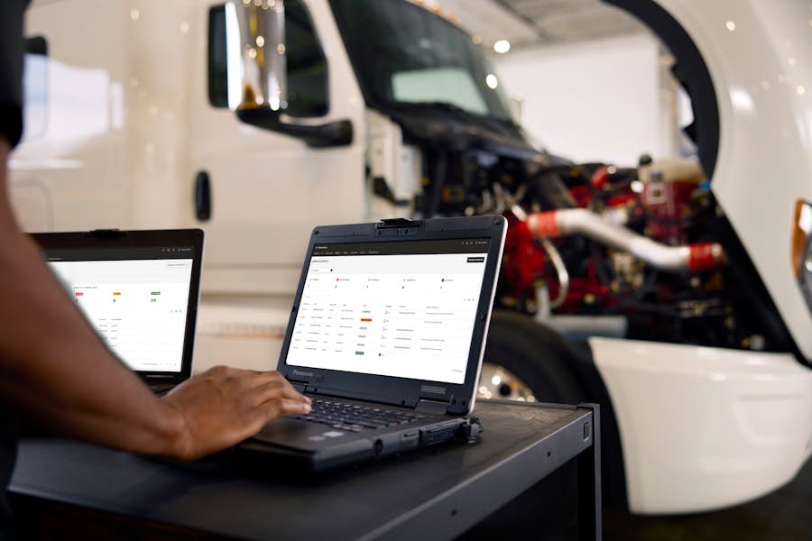 Technician using a laptop beside an International truck with the hood open