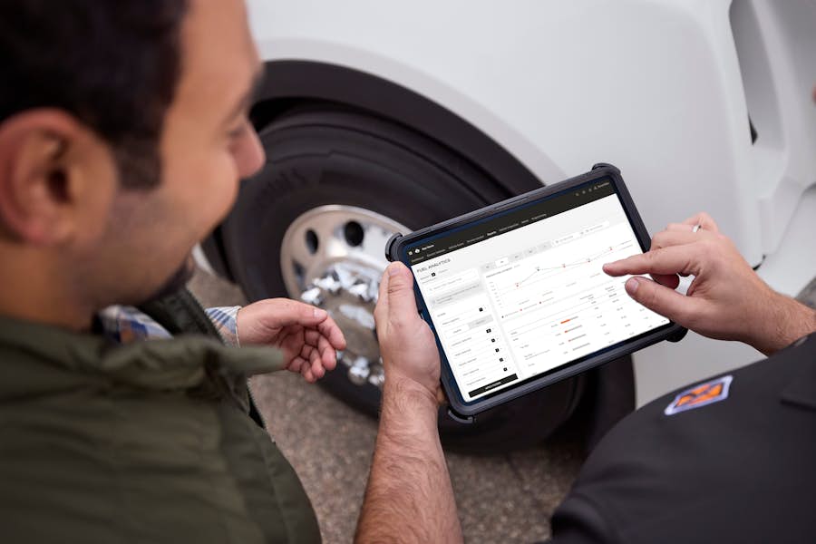 Technician reviewing a My International report on a tablet next to a truck wheel
